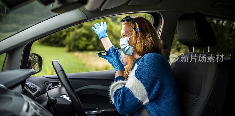 戴着防护面罩和手套开车的女人。世界大流行。保持安全。COVID - 19